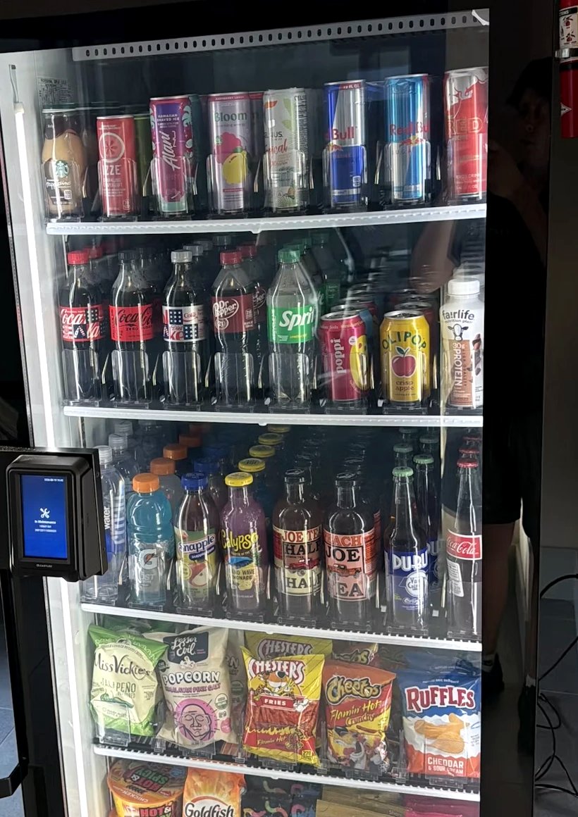 Smart cooler shelves stocked with soda, water, chips, and candy